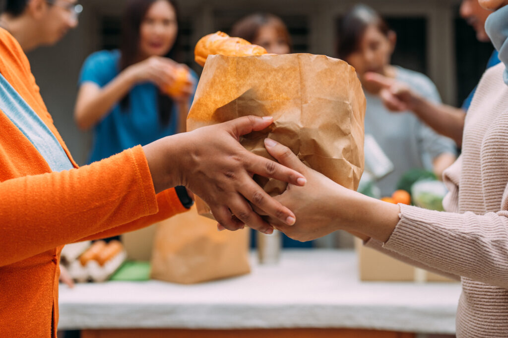 Unrecognizable woman hands out food donations during charity drive